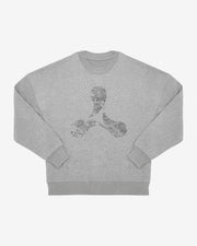 The Creamfields 2025 Oversized Grey Sweatshirt by Creamfields features a light gray crewneck design with a subtle, abstract black three-pronged symbol in the center, intricate patterns, long sleeves, and ribbed cuffs.
