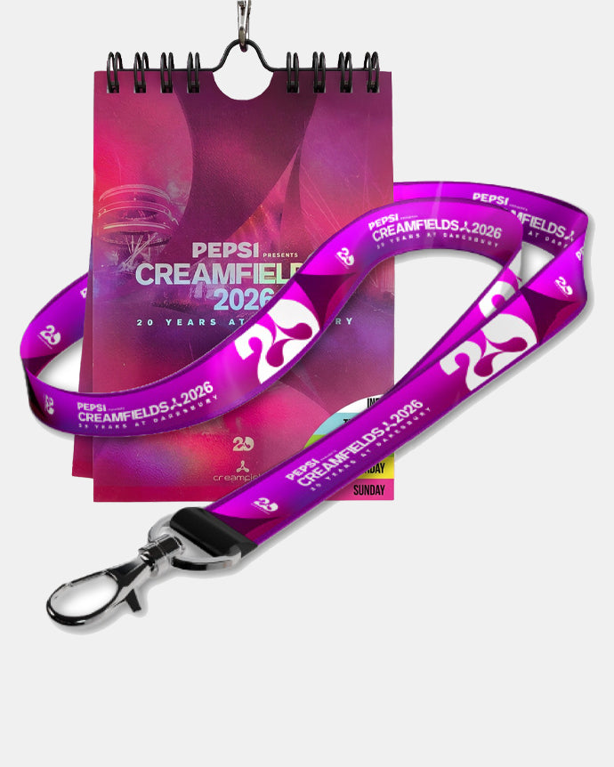 A Creamfields 2026 Click & Collect event lanyard featuring “25” and “Creamfields 2026” in purple is displayed next to a pink Creamfields 2026 calendar, celebrating the festival’s 25th anniversary.